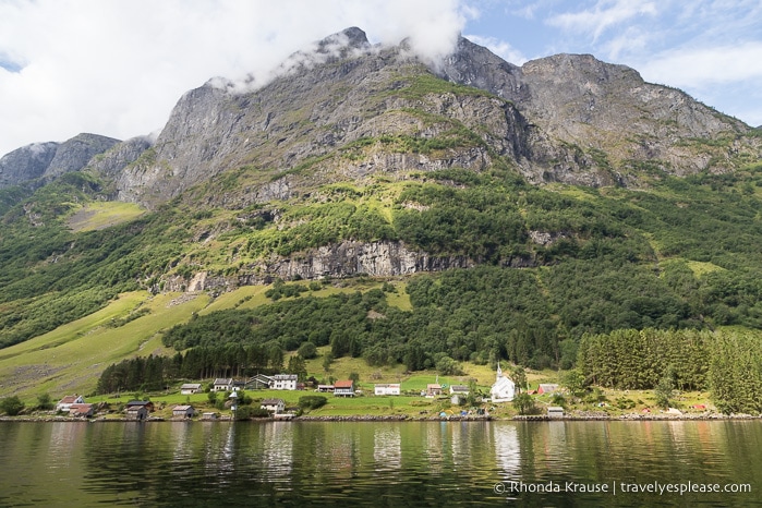 Small village on the shoreline of Naeroyfjord with a towering mountain in the background.