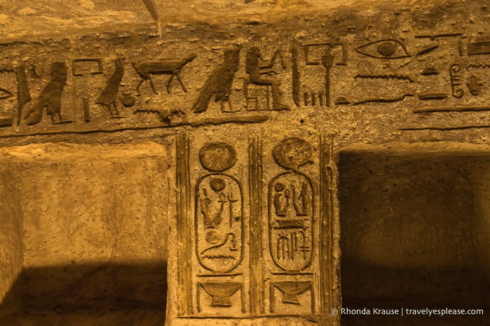 Hieroglyphs and cartouches around two niches in the wall.