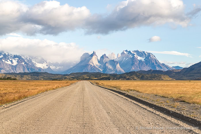 Gravel road leading towards mountains.