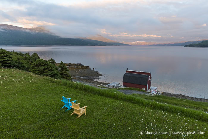 Empty chairs on the lawn of Neddies Harbour Inn overlooking Bonne Bay at sunset.